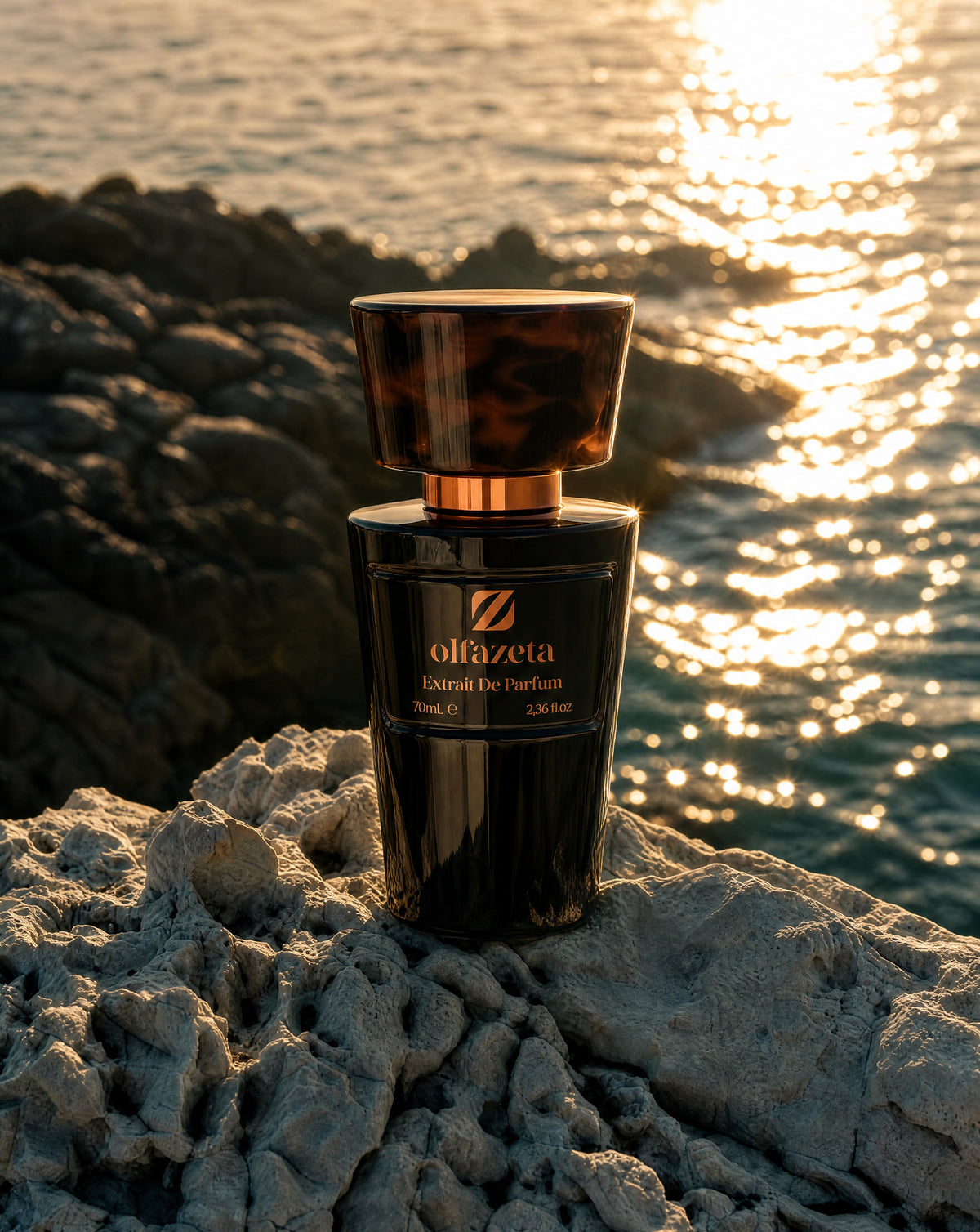 Frasco negro Olfazeta by Chogan Millésime, tapón de carey, sobre rocas claras frente al mar reluciente