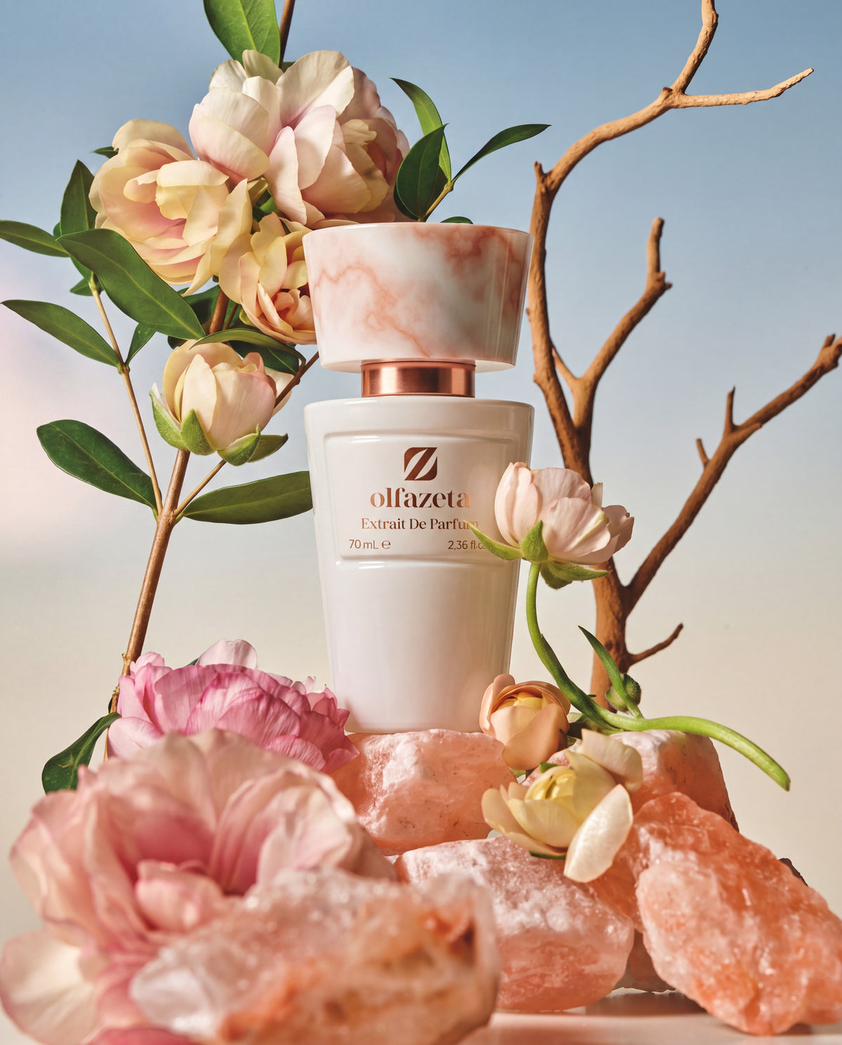 Witte flacon Olfazeta by Chogan Millésime N°10 op roze zoutrotsen tussen bleke rozen en kale takken