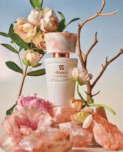 Witte flacon Olfazeta by Chogan Millésime N°10 op roze zoutrotsen tussen bleke rozen en kale takken